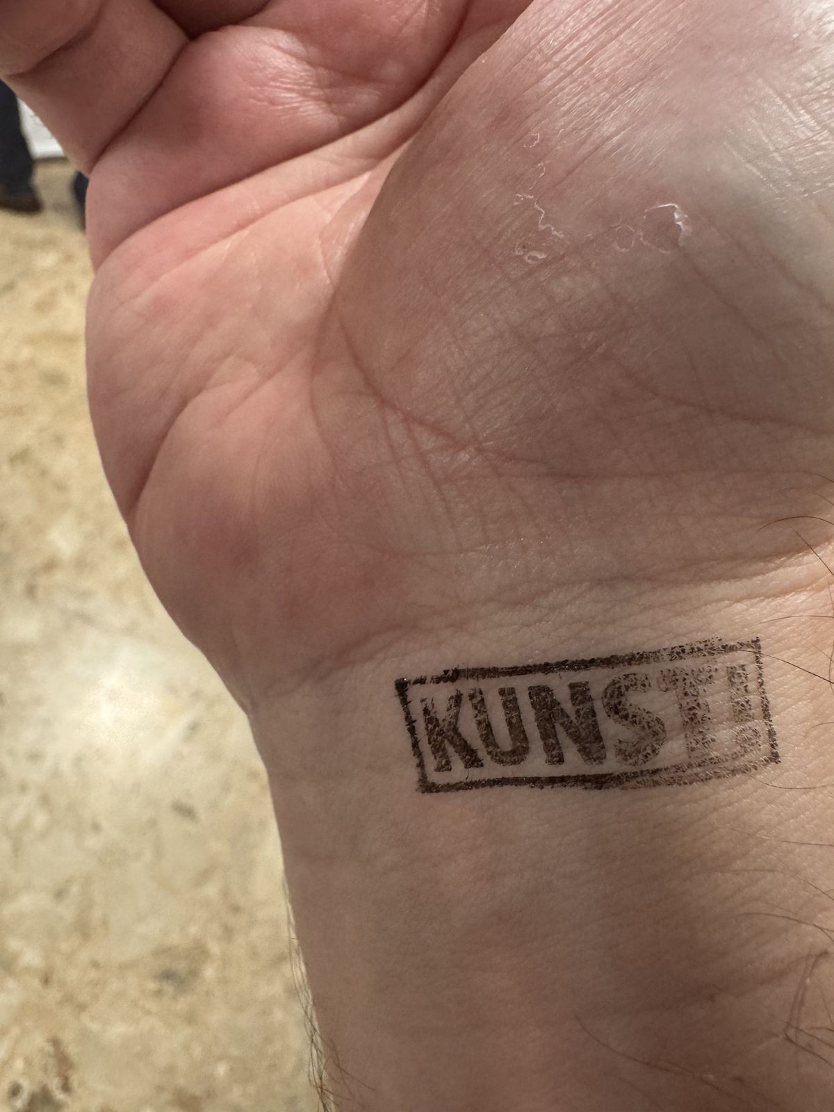 A photo of a hand with a stamp "Kunst!" (meaning "Art!") on the wrist